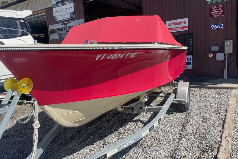 Slide: The Image of 2018 Rossiter 17 Closed Deck boat with red cover on trailer, parked outside dealership. - 5