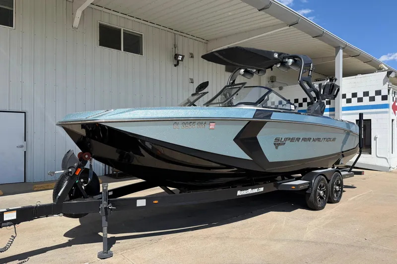 Slide: The Image of 2020 Nautique Super Air Nautique G25 boat on trailer, parked outside a building. - 2