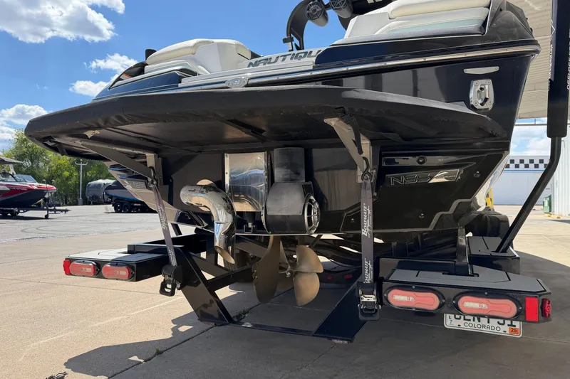 Slide: The Image of 2020 Nautique Super Air Nautique G25 boat rear view with trailer, showcasing propeller and exhaust. - 5