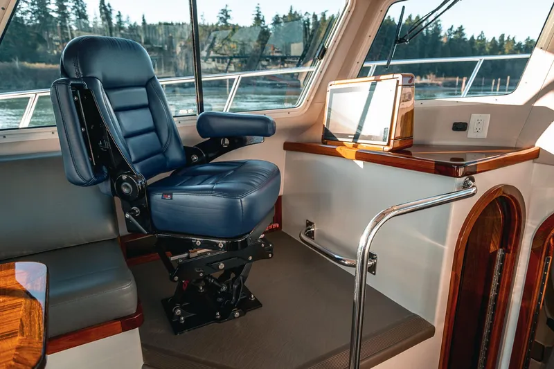 Slide: The Image of Captain's chair in 2019 Lindell 46' yacht interior, featuring blue leather and wood accents. - 12