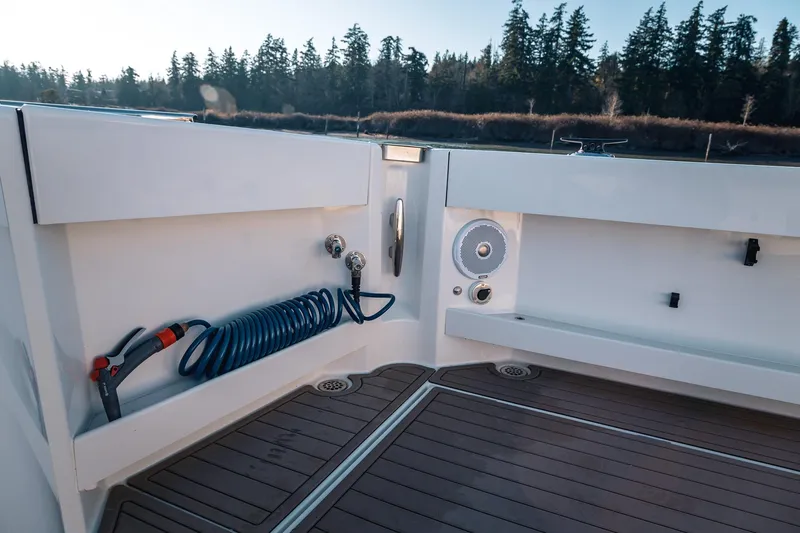 Slide: The Image of 2019 Lindell 46' boat deck with hose and speaker, surrounded by scenic forest. - 56