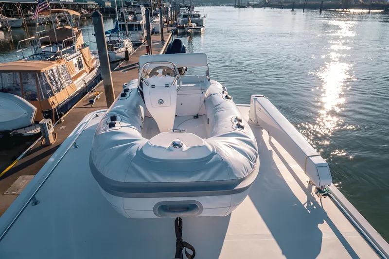 Slide: The Image of 2019 Lindell 46' yacht with inflatable boat docked at marina, sun reflecting on water. - 65