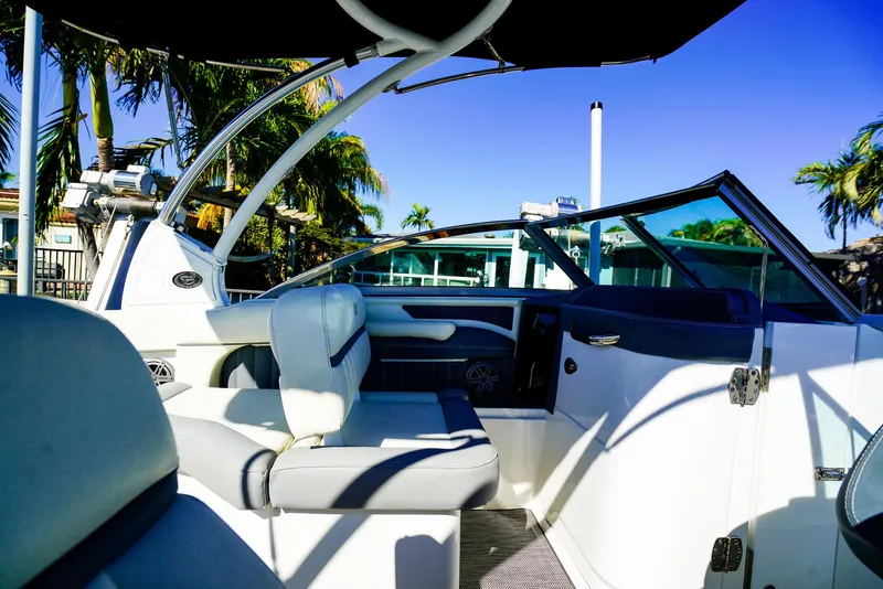 Slide: The Image of 2019 Cobalt 23SC boat interior with seating, palm trees, and blue sky background. - 12
