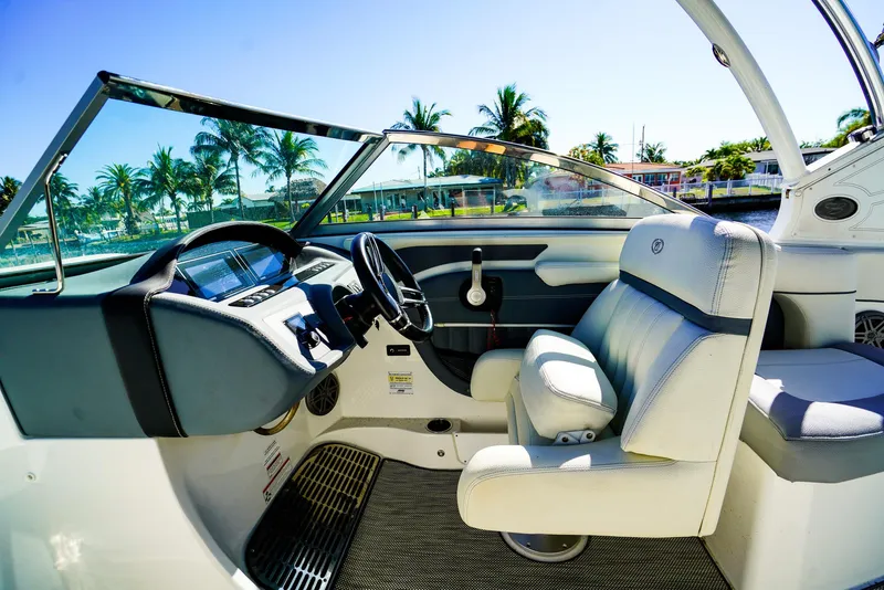 Slide: The Image of 2019 Cobalt 23SC boat interior with steering wheel, white seats, and tropical background. - 13