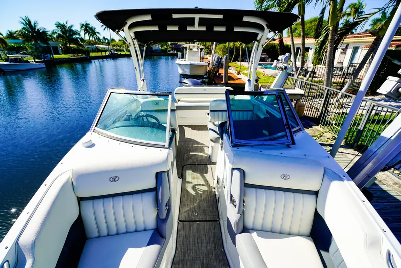 Slide: The Image of 2019 Cobalt 23SC boat interior with white seating, docked by a canal. - 16