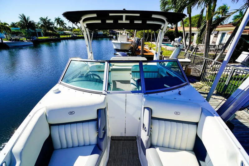 Slide: The Image of 2019 Cobalt 23SC boat with white seating, docked by a scenic waterfront. - 17