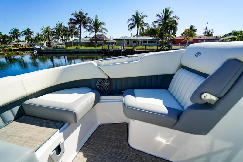 Slide: The Image of 2019 Cobalt 23SC boat interior with plush seating, set against a tropical waterfront backdrop. - 18