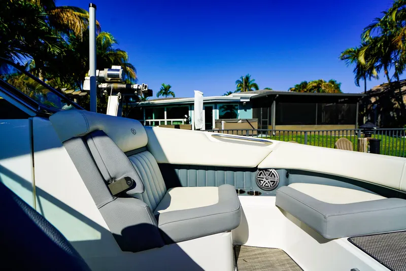 Slide: The Image of 2019 Cobalt 23SC boat interior with gray seating, palm trees, and blue sky background. - 19