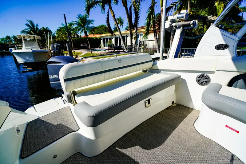 Slide: The Image of 2019 Cobalt 23SC boat interior with seating, docked near palm trees and water. - 2