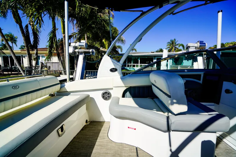 Slide: The Image of 2019 Cobalt 23SC boat interior with seating, palm trees, and clear blue sky. - 6