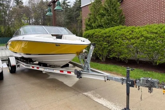 Slide: The Image of 2008 Regal 1900 Bowrider boat on trailer, yellow hull, parked near brick building. - 3