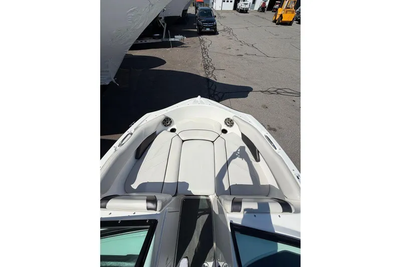 Slide: The Image of 2014 Yamaha Boats SX192 bow seating area with white upholstery in a parking lot. - 15