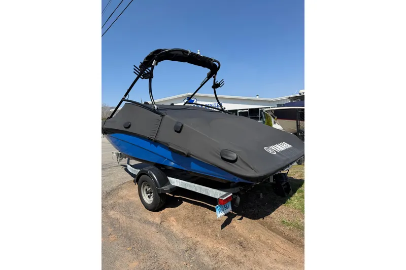Slide: The Image of 2014 Yamaha Boats SX192 with cover on trailer, parked outdoors under clear blue sky. - 4