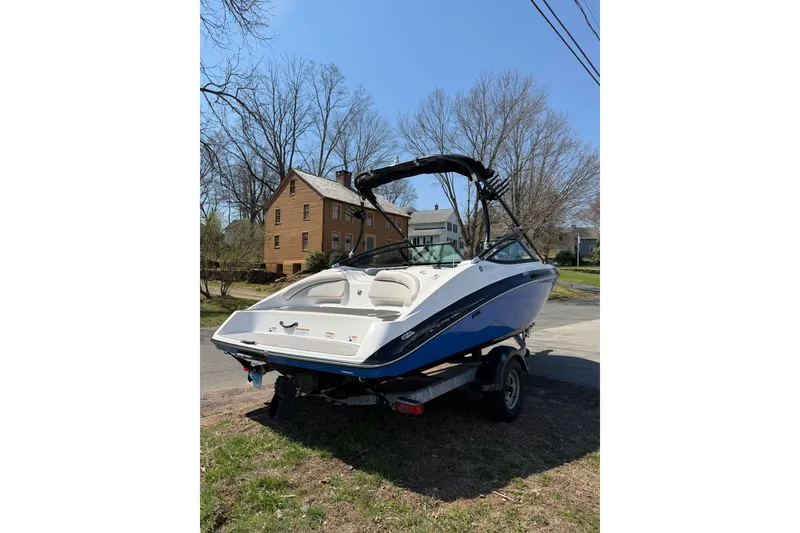 Slide: The Image of 2014 Yamaha Boats SX192 on trailer, parked near residential area, clear sky background. - 6