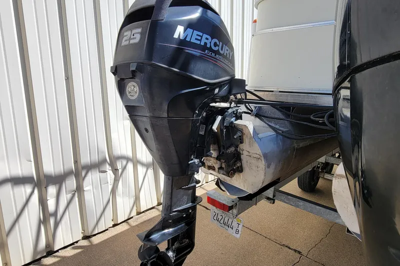 Slide: The Image of Mercury 25 horsepower outboard motor on 2003 Odyssey Millennium boat, parked near a metal building. - 5