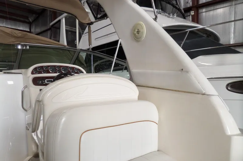 Slide: The Image of 1997 Sea Ray 290 Sundancer boat interior with white seating and dashboard in a storage facility. - 11