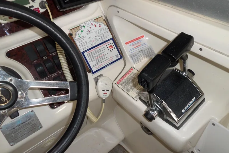 Slide: The Image of 1997 Sea Ray 290 Sundancer helm with steering wheel, throttle controls, and marine radio. - 22