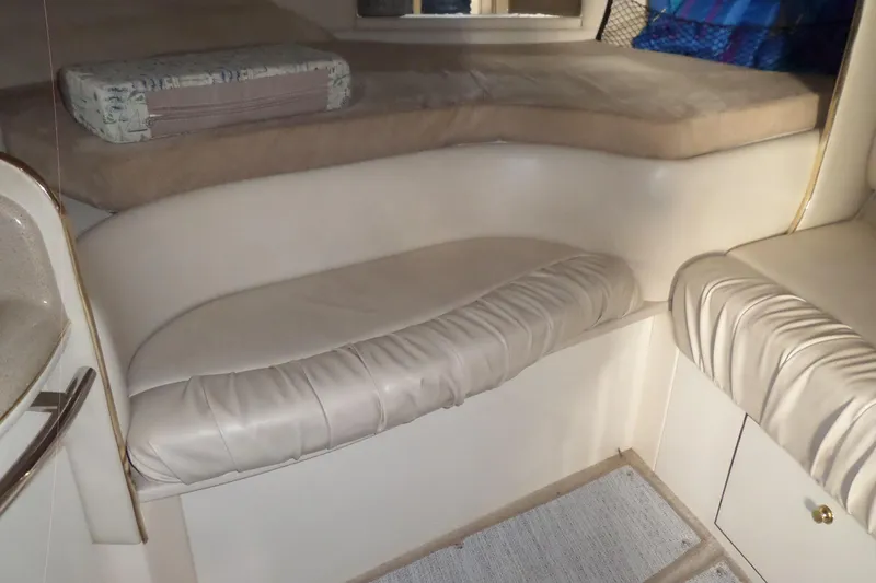 Slide: The Image of Interior cabin of a 1997 Sea Ray 290 Sundancer with cushioned seating and bedding. - 26