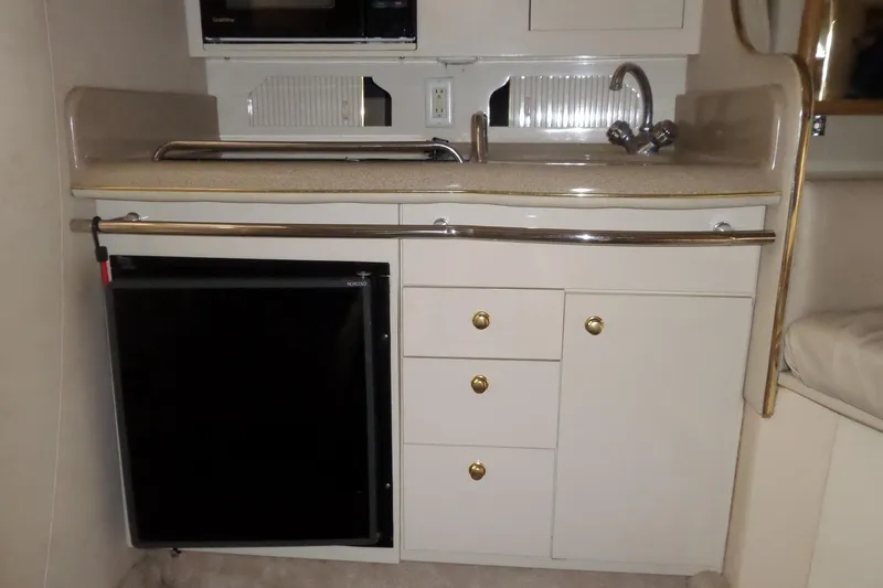 Slide: The Image of 1997 Sea Ray 290 Sundancer kitchenette with sink, fridge, and storage cabinets. - 28