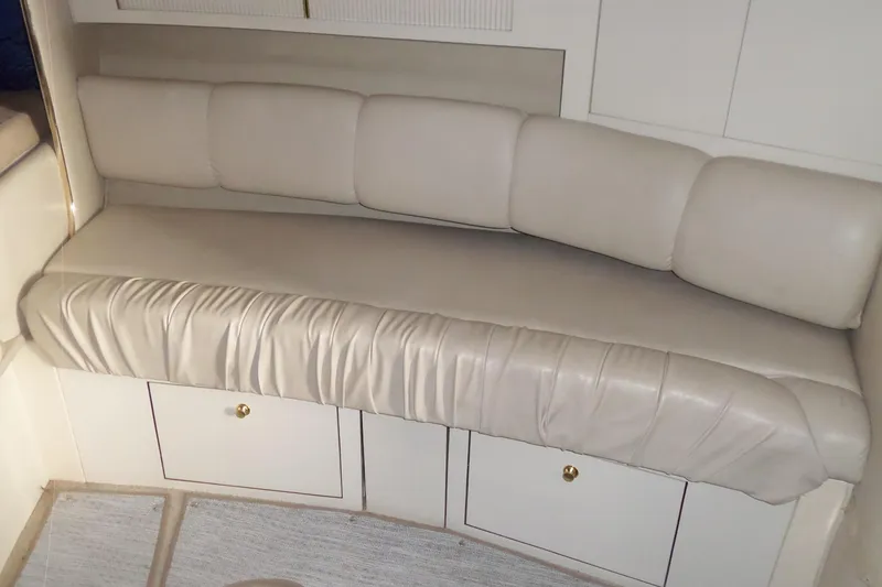 Slide: The Image of Interior seating of a 1997 Sea Ray 290 Sundancer boat, featuring beige upholstery. - 38