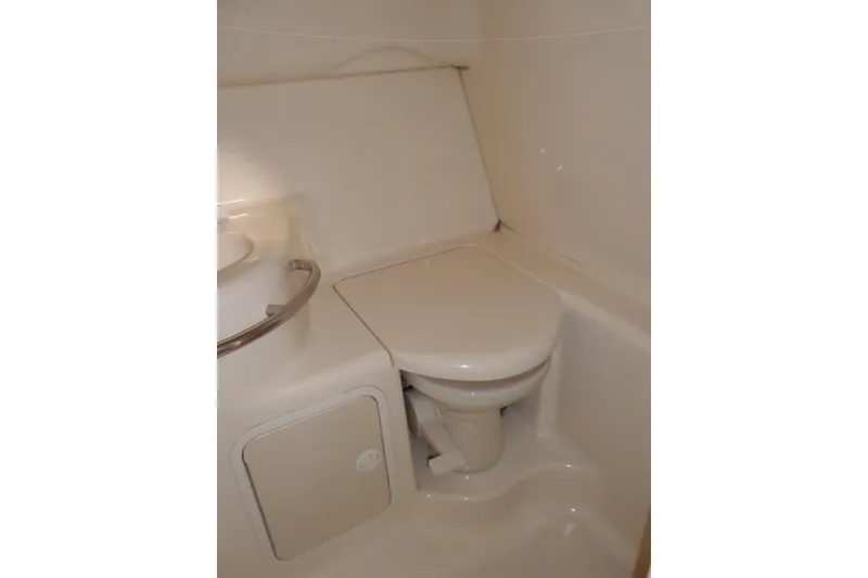 Slide: The Image of 1997 Sea Ray 290 Sundancer boat bathroom with compact toilet and storage compartment. - 42