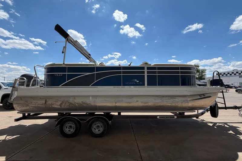 Slide: The Image of 2017 Bennington SX 22 Quad Bench pontoon boat on trailer under blue sky. - 6