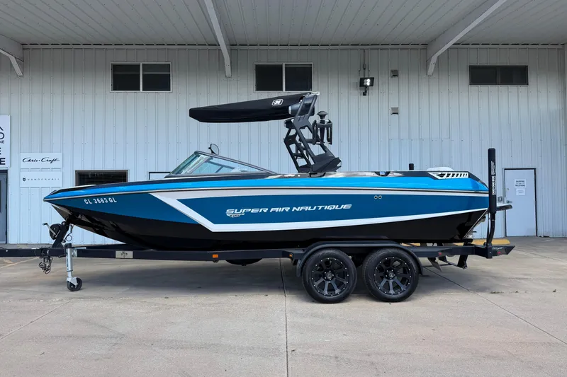 The Image of 2019 Nautique Super Air Nautique GS22 boat on trailer, blue and white design. - 1