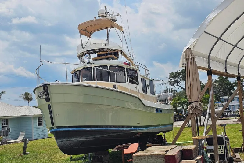The Image of 2014 Ranger Tugs R-31 CB boat on land, under a canopy, with clear sky background. - 0