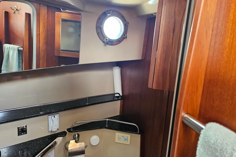 Slide: The Image of Bathroom interior of 2014 Ranger Tugs R-31 CB with wood accents and porthole window. - 16