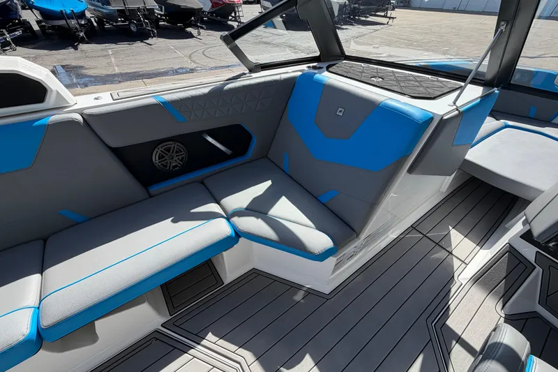Slide: The Image of 2025 Nautique Super Air Nautique GS24 interior with blue and gray seating, docked outdoors. - 14