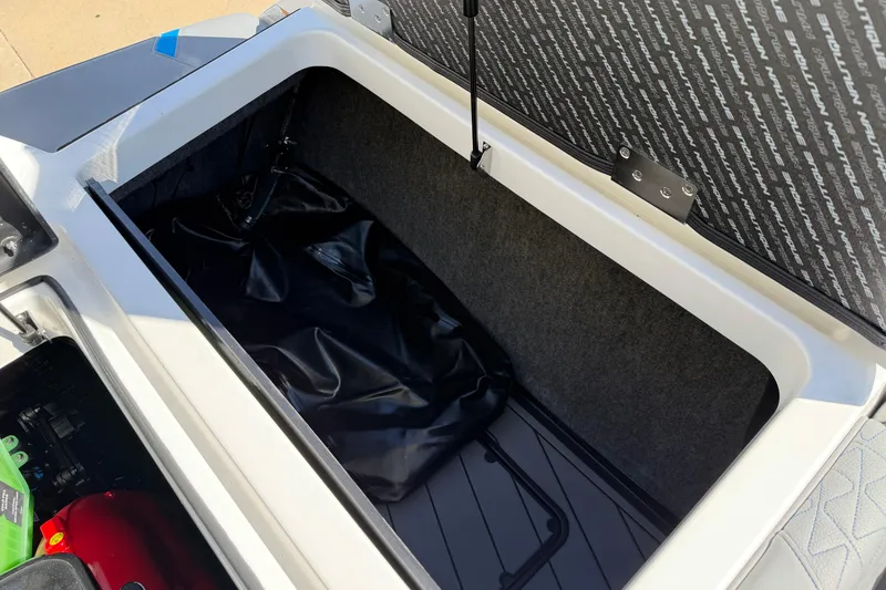 Slide: The Image of 2025 Nautique Super Air Nautique GS24 storage compartment with open lid and visible interior. - 17