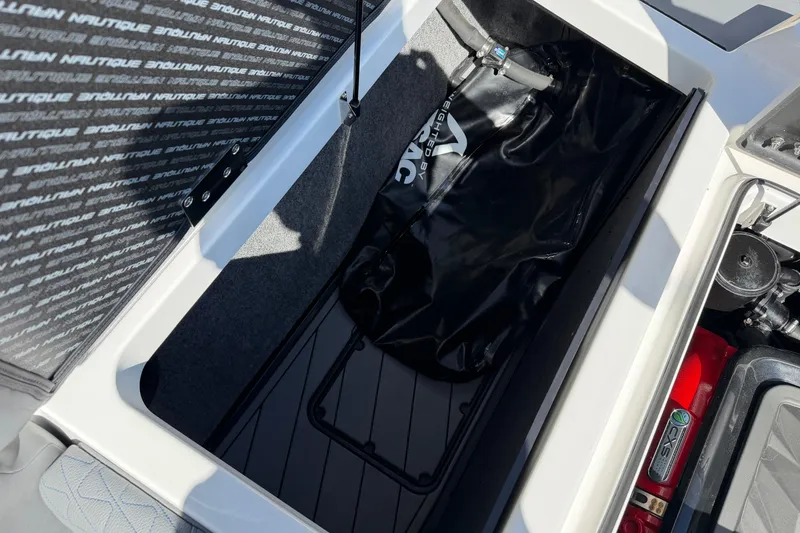 Slide: The Image of 2025 Nautique Super Air Nautique GS24 storage compartment with ballast bag and engine components. - 18
