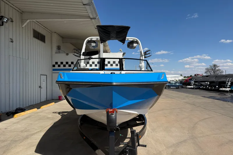 Slide: The Image of 2025 Nautique Super Air Nautique GS24 boat in blue, parked outdoors under clear skies. - 8