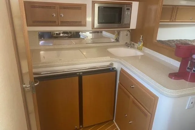 Slide: The Image of 2009 Cabo 35 Express yacht kitchen with microwave, sink, and wooden cabinetry. - 13