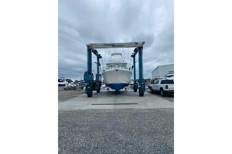 Slide: The Image of 2009 Cabo 35 Express boat on a lift at a marina, cloudy sky background. - 2