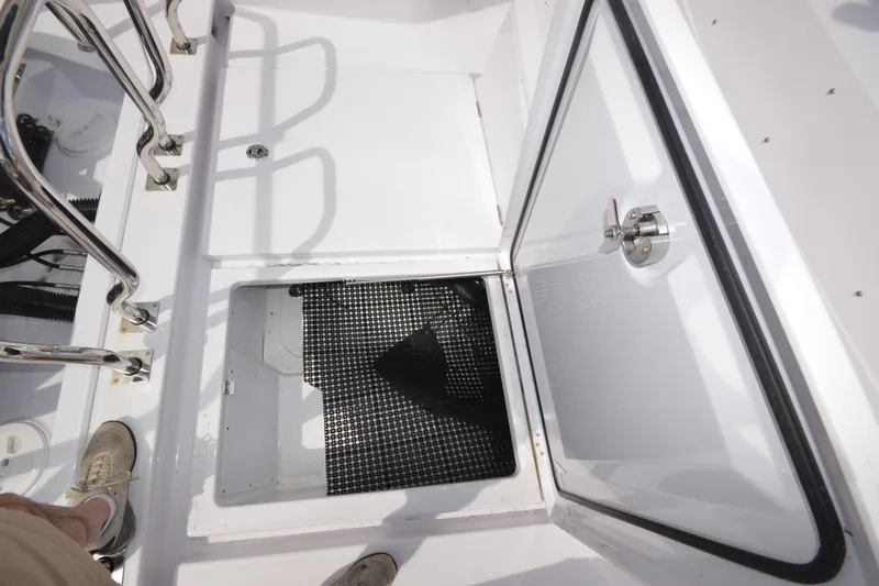 Slide: The Image of 2024 Axopar 37 XC Cross Cabin storage compartment with open hatch and stainless steel railing. - 14