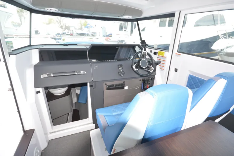 Slide: The Image of 2024 Axopar 37 XC Cross Cabin interior with modern helm and blue seating. - 22