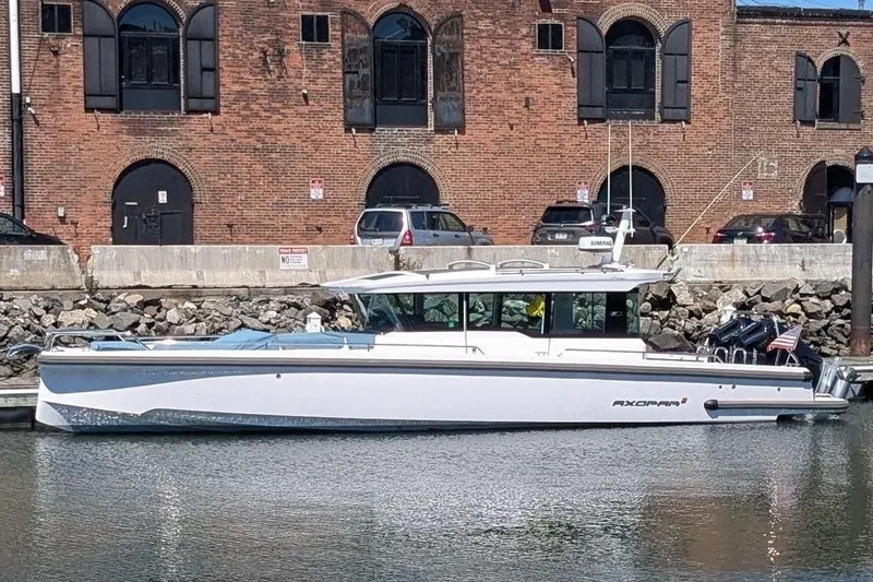 Slide: The Image of 2024 Axopar 37 XC Cross Cabin boat docked by a brick building. - 46