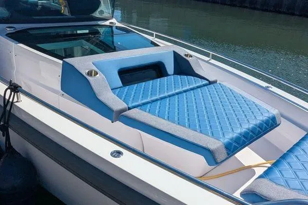 Slide: The Image of 2024 Axopar 37 XC Cross Cabin with blue quilted seating, docked by the water. - 48