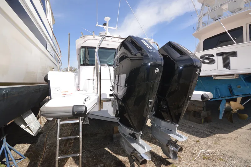 Slide: The Image of 2024 Axopar 37 XC Cross Cabin with dual outboard engines, docked between boats. - 8