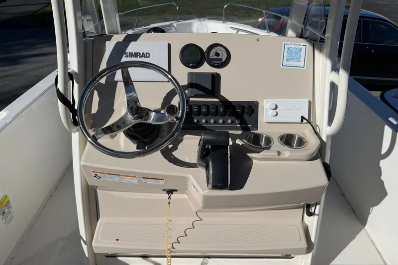Slide: The Image of 2023 Boston Whaler 220 Dauntless boat console with steering wheel and controls. - 2