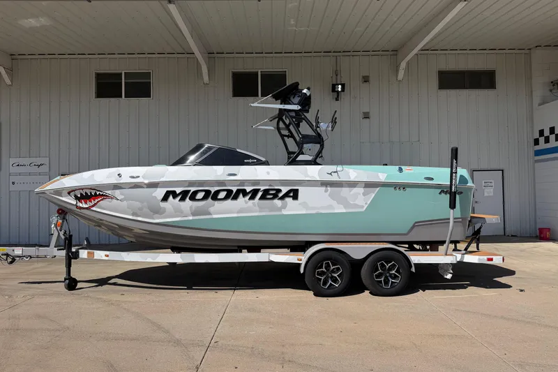 The Image of 2025 Moomba Mojo boat with shark mouth design on trailer, parked outside a building. - 1