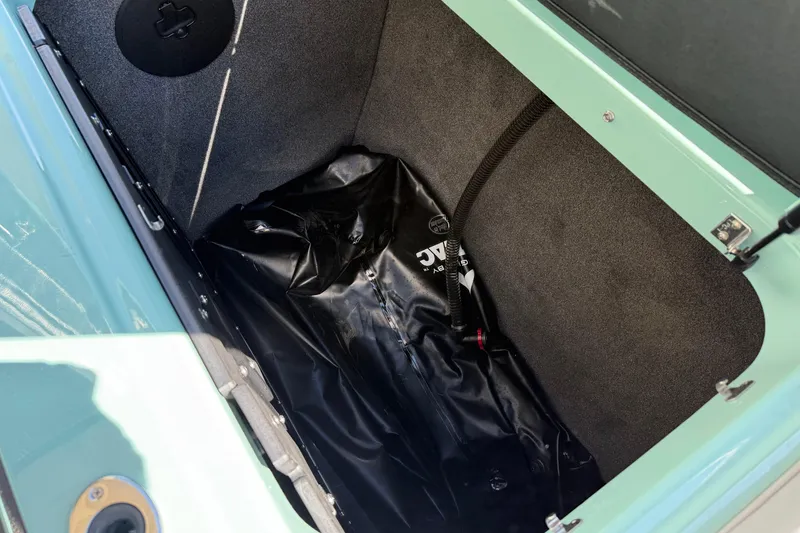 Slide: The Image of 2025 Moomba Mojo boat storage compartment with black ballast bag and carpeted interior. - 17