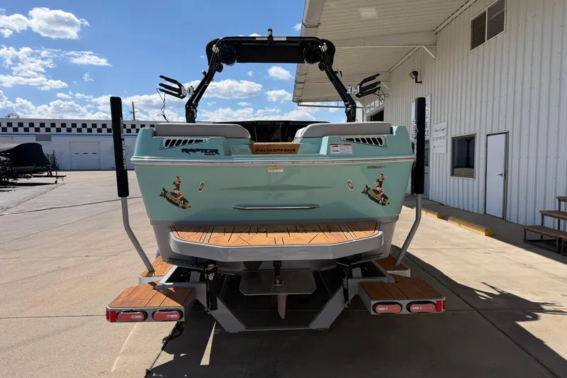 Slide: The Image of 2025 Moomba Mojo boat, rear view, parked outdoors under a clear blue sky. - 4