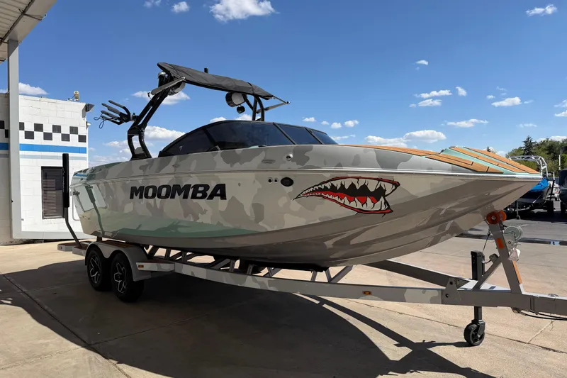 Slide: The Image of 2025 Moomba Mojo boat with shark design on trailer under clear blue sky. - 7