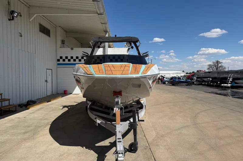 Slide: The Image of 2025 Moomba Mojo boat on trailer outside a warehouse under a clear blue sky. - 8