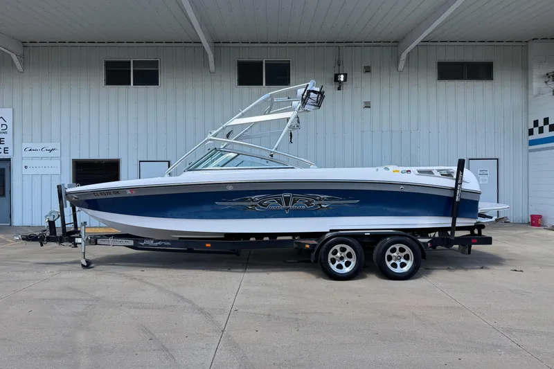 The Image of 2007 Nautique Crossover 236 boat on trailer, parked outside a building. - 1