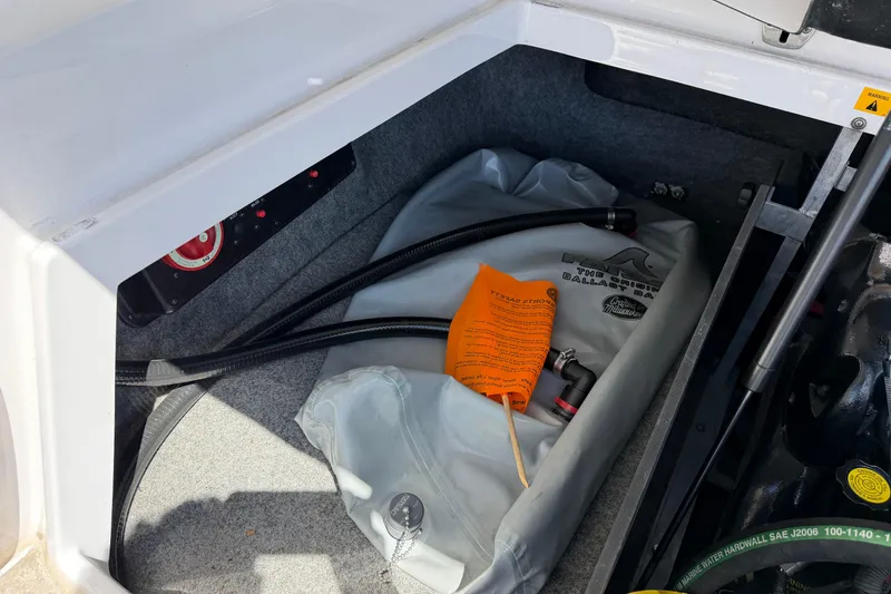 Slide: The Image of 2007 Nautique Crossover 236 storage compartment with ballast bag and hoses. - 19