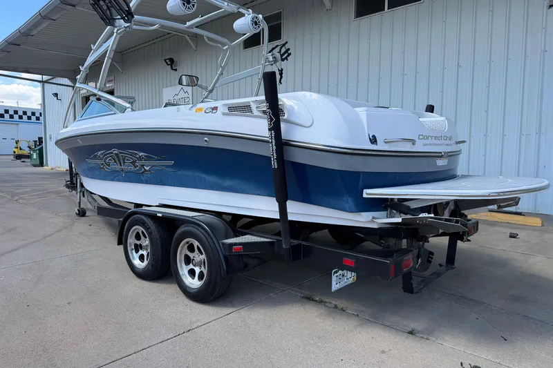 Slide: The Image of 2007 Nautique Crossover 236 boat on trailer, parked outside a building. - 3