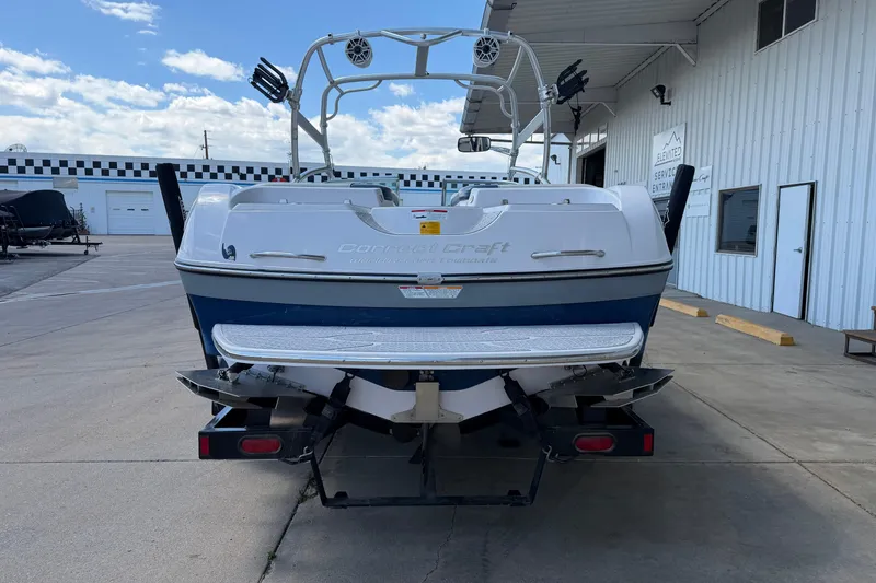 Slide: The Image of 2007 Nautique Crossover 236 boat on trailer, parked outside a service entrance. - 4